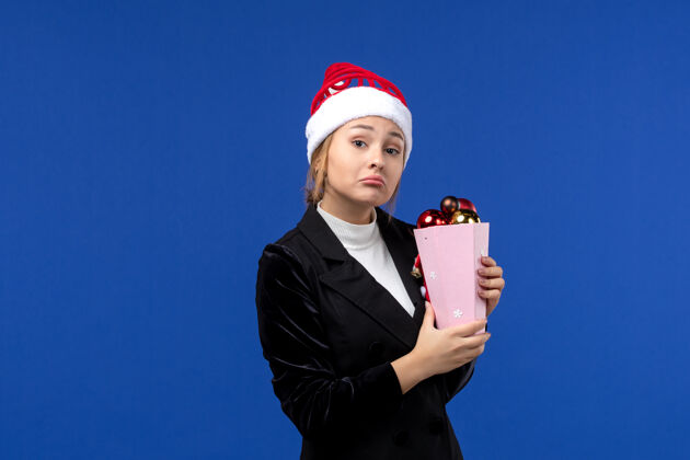 人前视图年轻女性手持蓝色背景新年假期情感色彩的圣诞树玩具年轻女性公司成功