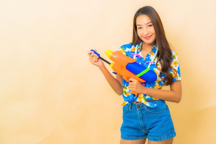 惊人美丽的亚洲年轻女子身穿彩色衬衫 手持水枪的肖像文化女人度假