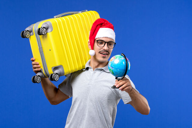 人正面图年轻男子背着黄包上了蓝墙飞机度假旅行男年轻男性人圣诞节