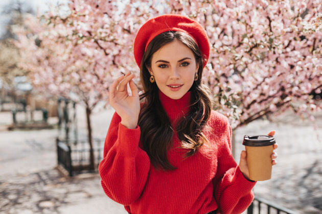 咖啡穿着红毛衣的美女带着樱花走在大街上 喝着咖啡戴着贝雷帽的美女微笑着在外面喝茶年轻花花