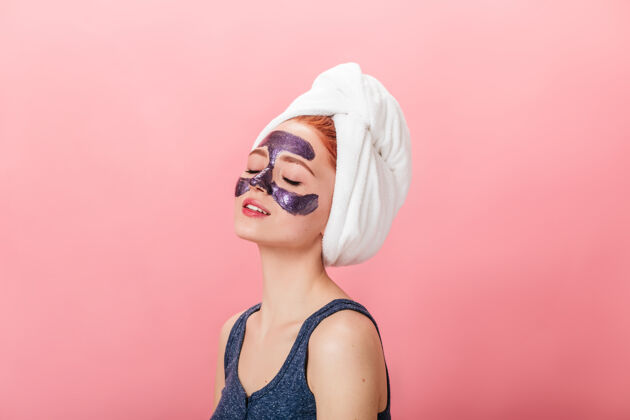 擦洗放松的年轻女子在粉红色的背景下做水疗摄影棚拍摄的戴着面具的女孩闭着眼睛摆姿势自然面部健康