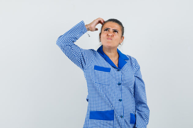 睡衣一个年轻的女人 手举在头上 想着什么东西 穿着蓝色格子睡衣 看起来很漂亮正面图衬衫手女性