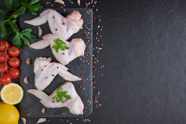 饮食带烹饪原料的生鸡翅生肉鸡翅放在木板上 黑色背景上有蔬菜和香料有机营养混合