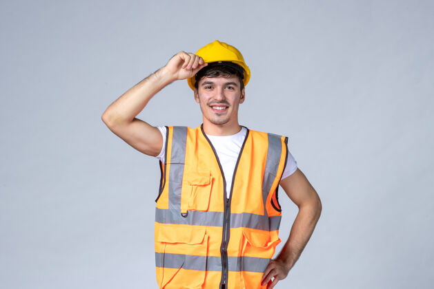 建筑正面图身穿制服的年轻男性建筑工人戴着白色背景的防护头盔制服建设者建设者