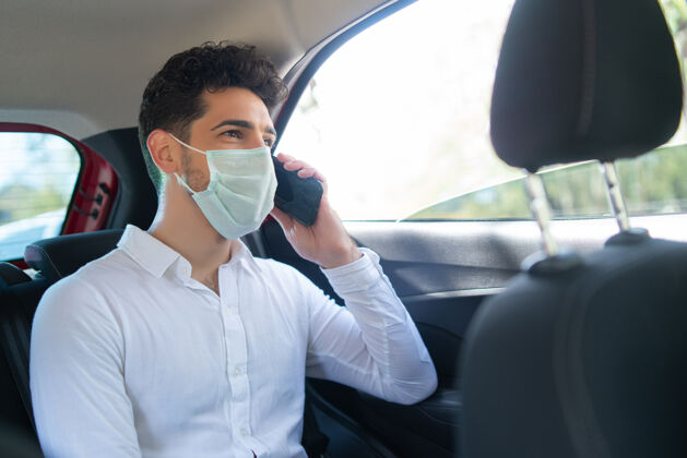 谈话在开车上班的路上戴着口罩打电话的商人的肖像商业概念新的正常生活方式概念面罩后座男士