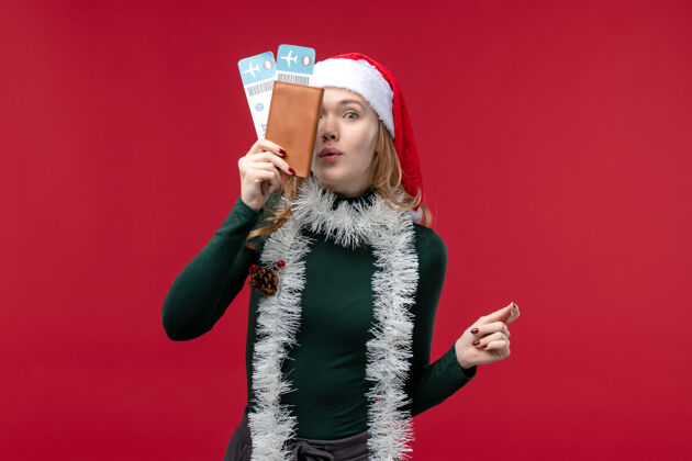 圣诞节正面图红色背景的年轻女性拿着票前面票脸