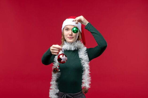 人物正面图红色背景上手持圣诞树玩具的年轻女性年轻女性红色圣诞节