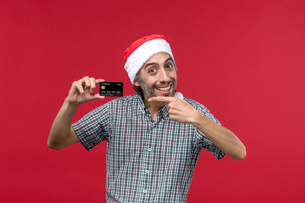 男人正面图年轻男子手持红色背景的黑色银行卡圣诞节男人人