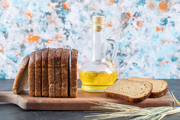 新鲜棕色面包片和油瓶放在木板上食品玻璃木头