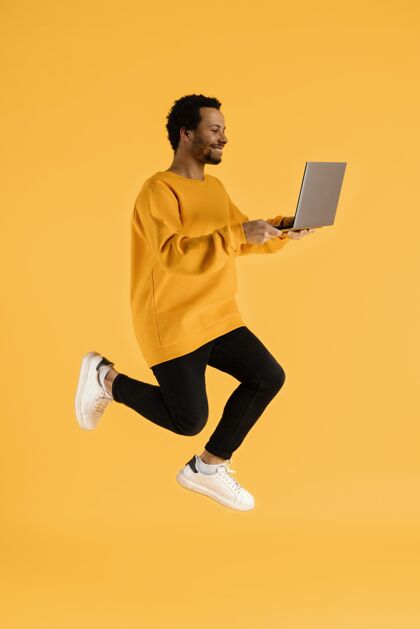 男人一个拿着笔记本电脑的年轻人模型笔记本电脑跳跃