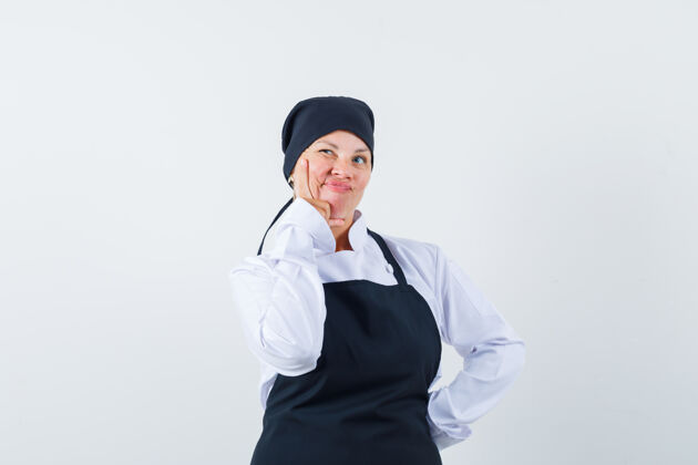 举行穿着黑色厨师制服的金发女人把食指放在嘴边 看起来很沉思嘴巴皮肤女性