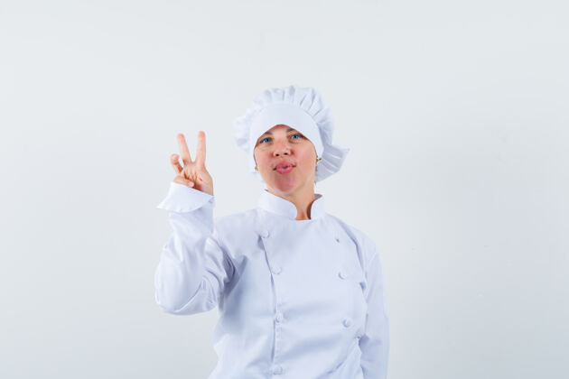 女性一个金发女人穿着白色的厨师制服展示着和平的标志 看起来很漂亮金发自然年轻