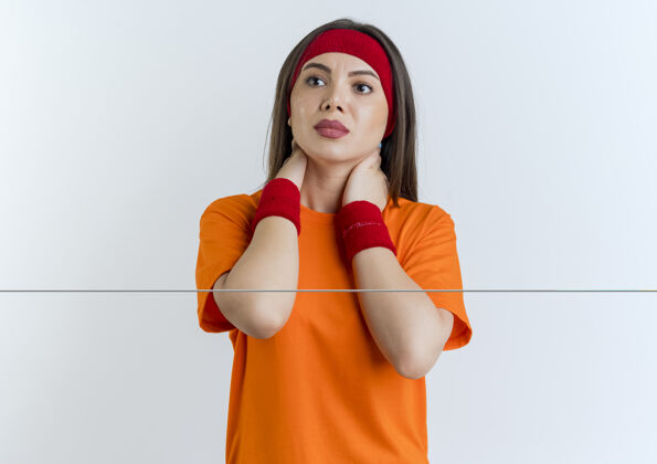 女人年轻的运动女性戴着头带和腕带看着侧面把手放在脖子上隔离在白色的墙壁上复制空间年轻壁板运动