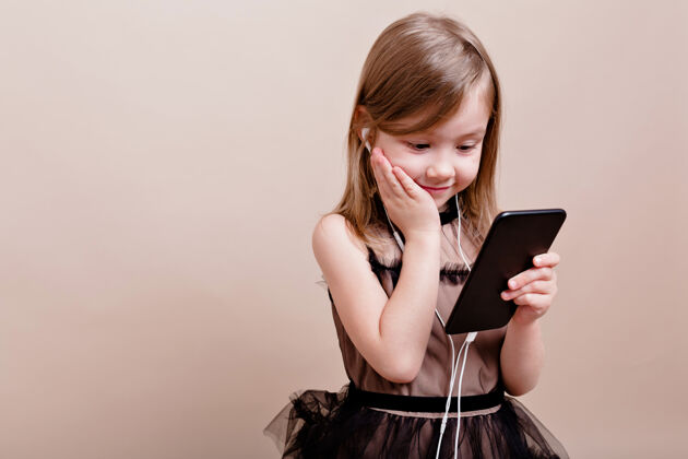 惊喜兴奋的小女孩收到了一个新的手机 并享受它可爱的女孩与真正的情感手持智能手机 听音乐与伟大的情感 地方的文字快乐魅力积极