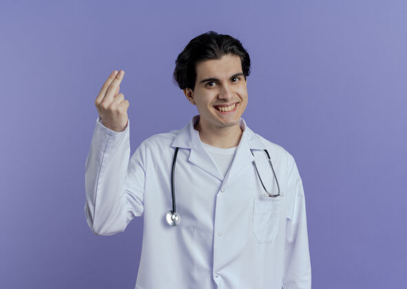 男性微笑的年轻男医生穿着医用长袍和听诊器 显示两只手被隔离在紫色的墙上 留有复印空间听诊器微笑年轻