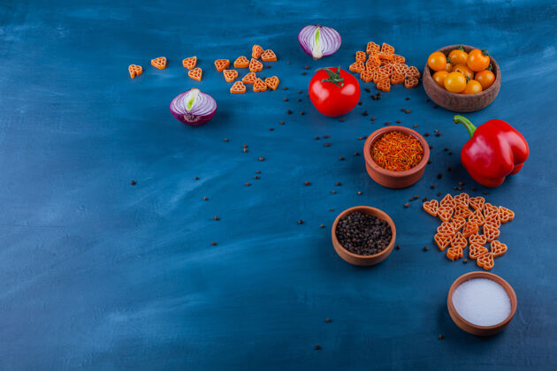 调味品成熟的新鲜蔬菜和各种调味品放在蓝色的表面上蔬菜铃铛生的