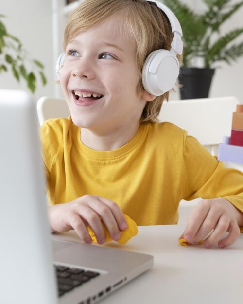 孩子戴耳机的男孩用笔记本电脑科技设备耳机