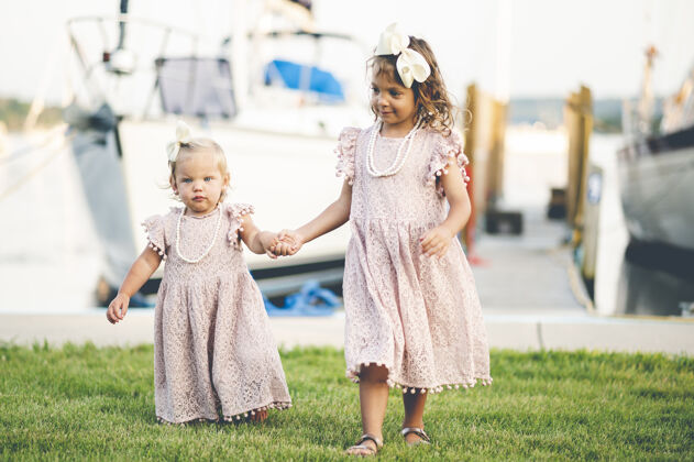 女孩两个穿着相似衣服的可爱女婴在港口附近散步的特写镜头童年女性快乐