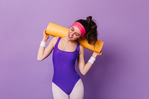 粉色袜子80年代风格的运动装美女照片 在紫色的墙上摆着健美操垫子黑发80年代风格人