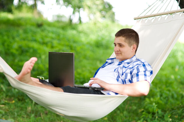 男人用笔记本电脑在吊床上工作休息放松阅读