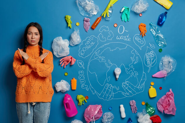 全球人 生态 禁止 拒绝概念严肃的亚洲女孩双臂交叉在胸前 对塑料说不 环保 站在蓝色的墙上垃圾储蓄室内