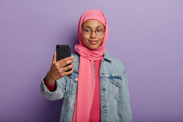 手机迷人的女性 面带微笑 通过智能手机拍照 按照宗教信仰穿着传统服装科技满意女人