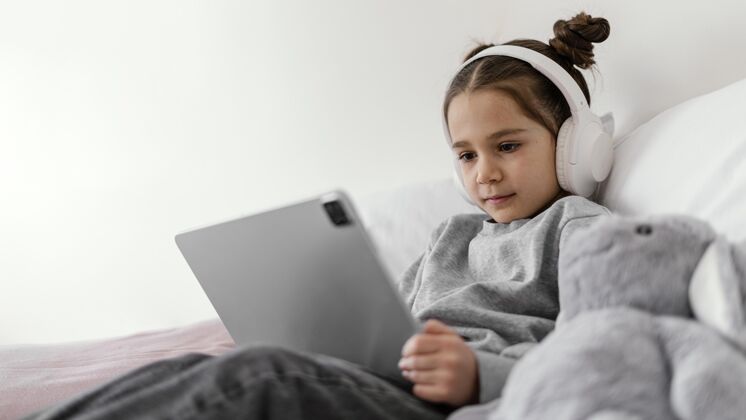 房子小女孩在床上用耳机用平板电脑平板电脑孩子女孩