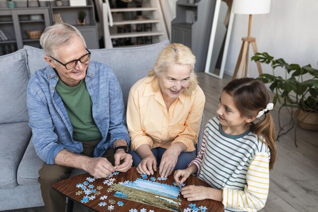 家庭爷爷奶奶和女孩在玩拼图中枪室内女人休闲
