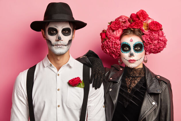 墨西哥水平拍摄的幽灵夫妇穿着墨西哥的死亡日 戴着头骨面具 站在一起 庆祝万圣节一起 隔离在粉红色的背景恐怖传统成人