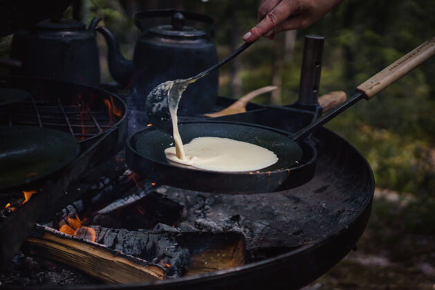 野营一个人在户外篝火上做煎饼的特写镜头早上美味吃
