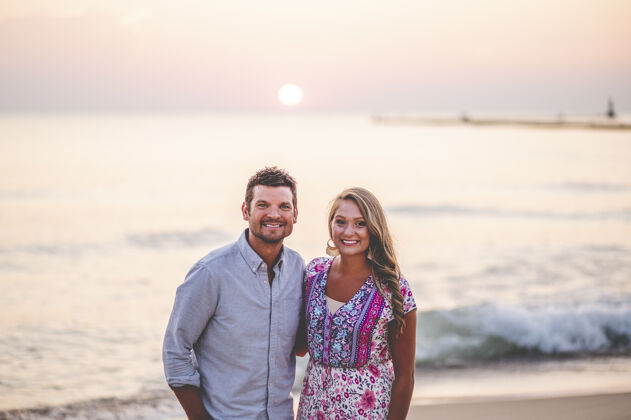 微笑一对年轻夫妇在美丽的海景前摆姿势的美丽特写写真背景阳光日落