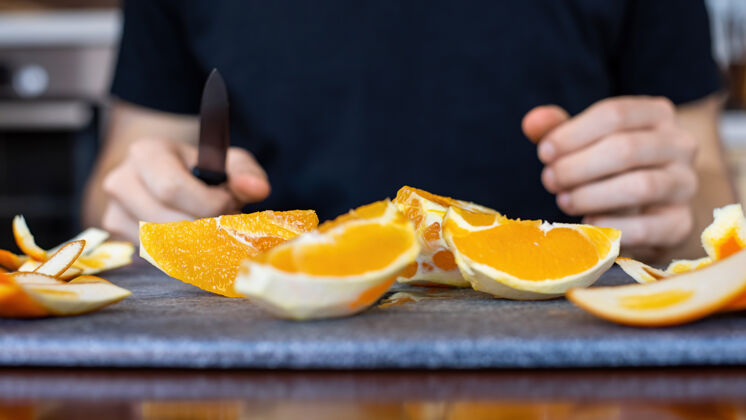 切割一个男人手里拿着一把刀 把橘子片放在烹饪板上有机季节老