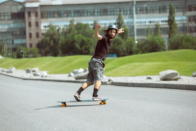 男孩在阳光明媚的日子里 滑板运动员在城市的街道上玩花样休闲男孩平衡