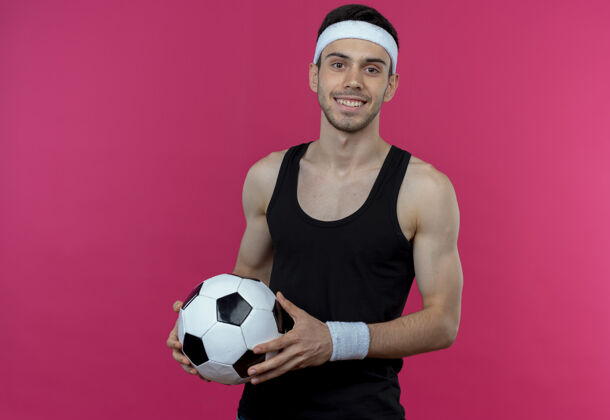 欢呼戴着头巾 手持足球 站在粉红色的墙上欢快微笑的年轻人年轻运动微笑