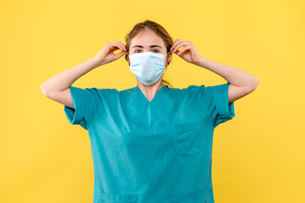 女医生正面图黄色背景上戴无菌口罩的女医生大流行健康病毒肖像护目镜病毒