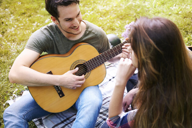 爱好情侣在公园野餐男吉他浪漫的约会浪漫玩休息