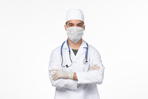 面具正面图：男医生穿着医疗服 戴着防毒面具 在白墙上传播病毒-病毒-疾病大流行专业疾病男性