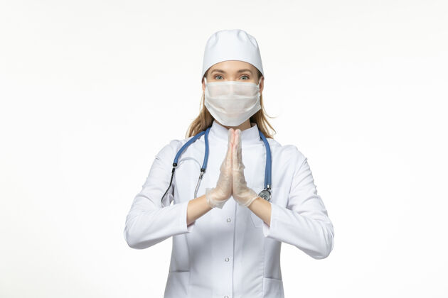疾病前视女医生穿着医疗服戴口罩因冠状病毒在浅白的办公桌上传播疾病冠状病毒-大流行病毒疾病佩戴到期听诊器