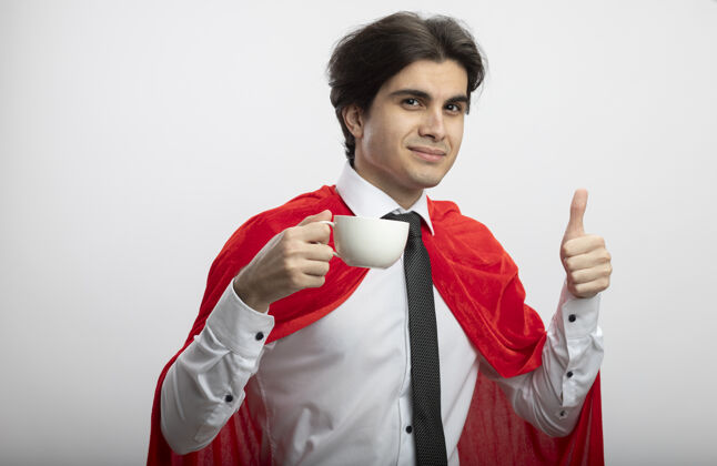 领带年轻的超级英雄戴着领带 端着一杯茶 在白色的地板上竖起大拇指向上大拇指年轻