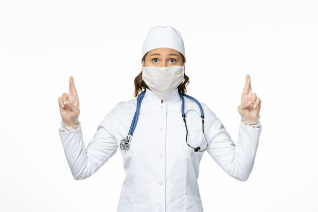 大流行前视女医生身穿白色医疗服戴口罩因冠状病毒对光壁大流行性疾病病毒隔离套装听诊器佩戴