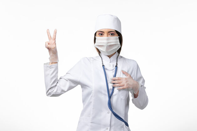 面罩正面图女医生身穿白色医疗服 戴口罩 因大流行于光墙上 医学大流行病毒covid-人员女性视图