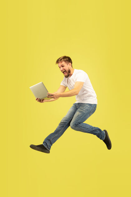 运动黄色背景上孤立的快乐跳跃人的全长肖像穿着休闲服的白人男模跳跃男性广告