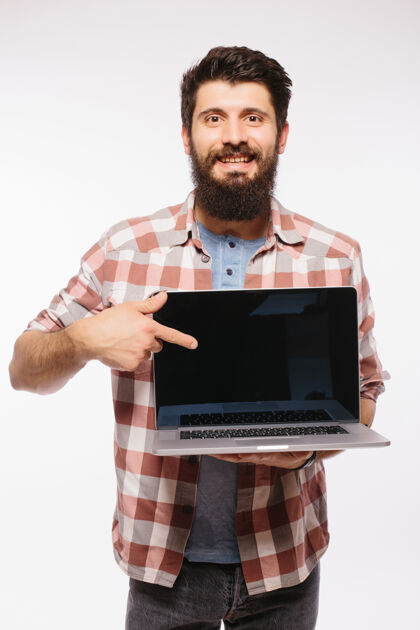 立场快乐的笑脸胡子男人拿着黑屏笔记本电脑隔着白墙无线屏幕电脑