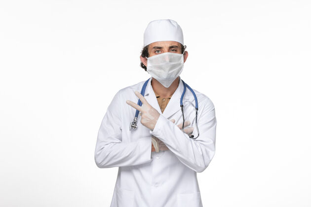 冠状病毒防护正面图男医生身穿医疗服 戴着防冠状病毒口罩上了淡白色的墙壁冠状病毒大流行药医疗视图专业