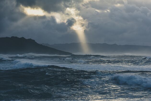 悬崖在一个多云的夜晚 波涛汹涌的大海掀起了波澜飞溅海地平线