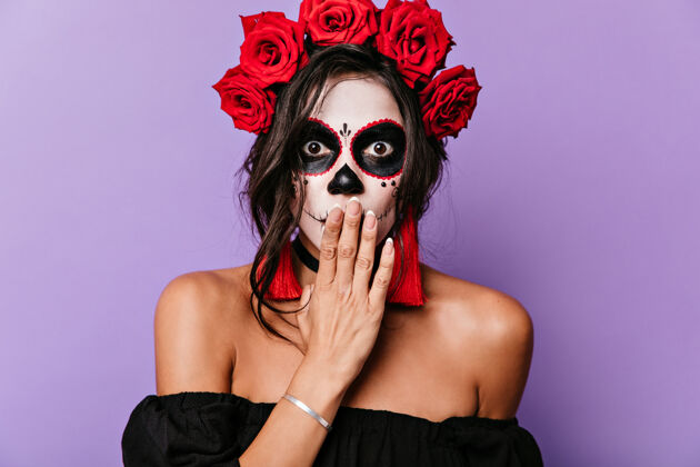 幻想为万圣节化妆的棕色眼睛的惊讶女孩的特写肖像戴着玫瑰花冠的成年妇女用手捂住她的嘴以防震惊人物人体艺术墨西哥