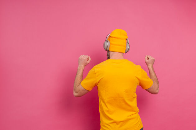 听力帅哥带着粉色背景上的耳机随意跳舞情人收音机手势