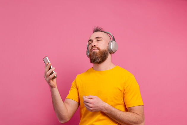 耳机帅哥带着手机和耳机在粉色背景上翩翩起舞粉色旋律头发