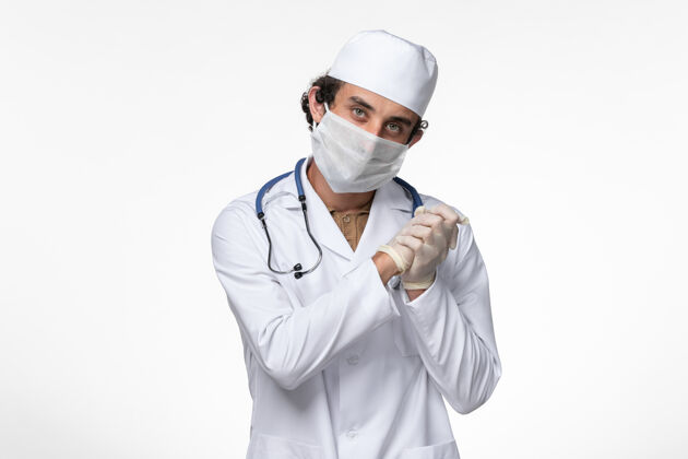 大流行正面图：男医生穿着医疗服 戴着口罩 以防柯维德病毒-白色办公桌上的疾病-柯维德病毒-大流行男性正面防护