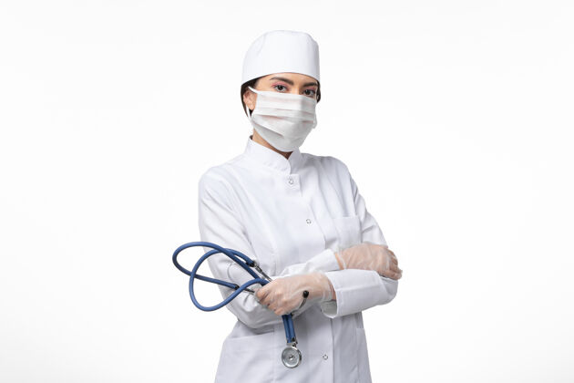 医生正面图女医生穿着白色无菌医疗服 戴着口罩 由于白墙疾病 病毒大流行女性大流行病毒